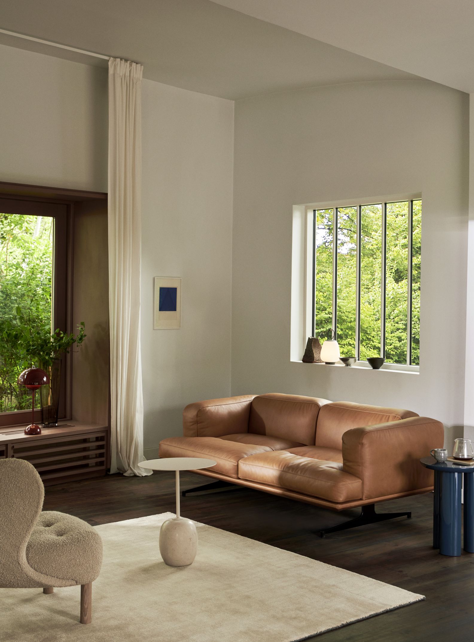 AndTradition Inland Sofa AV22/AV23 aus braunem Leder in modernem Wohnzimmer mit Teppich und Beistelltischen.