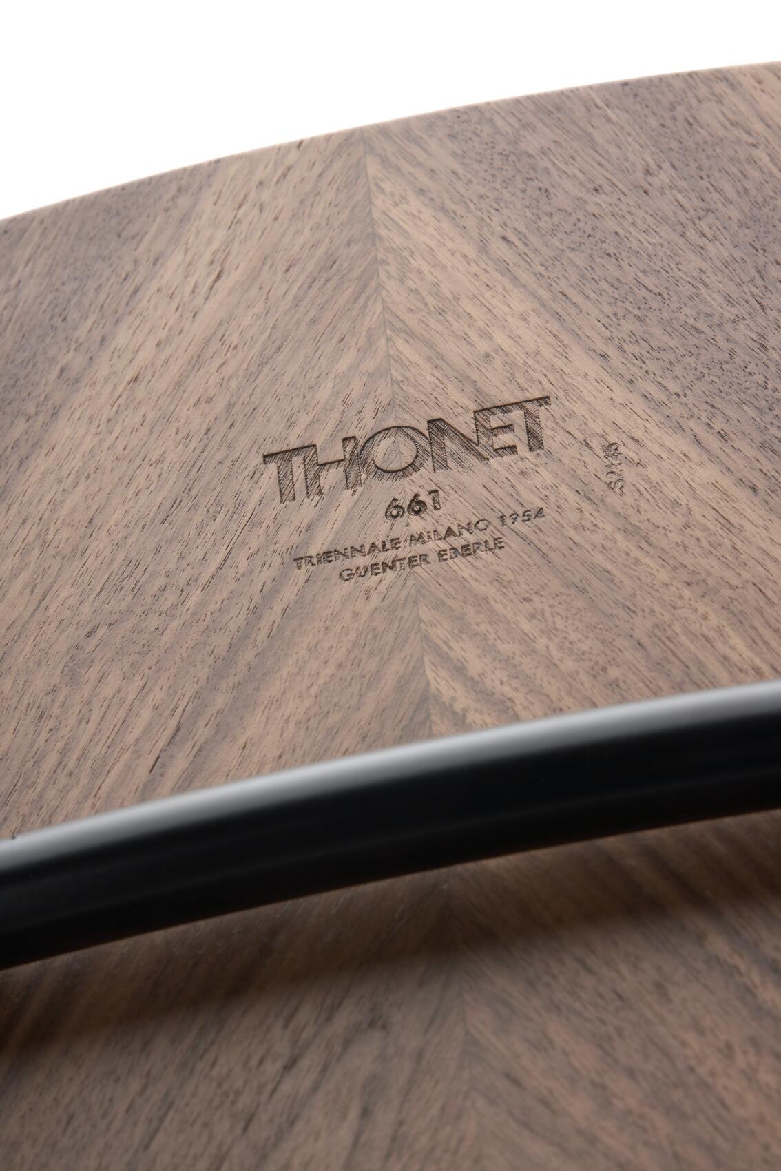 Detailaufnahme der Holzoberfläche des Thonet S 661 Stahlrohrstuhls mit eingraviertem Thonet-Logo und Stahlrohr-Element.