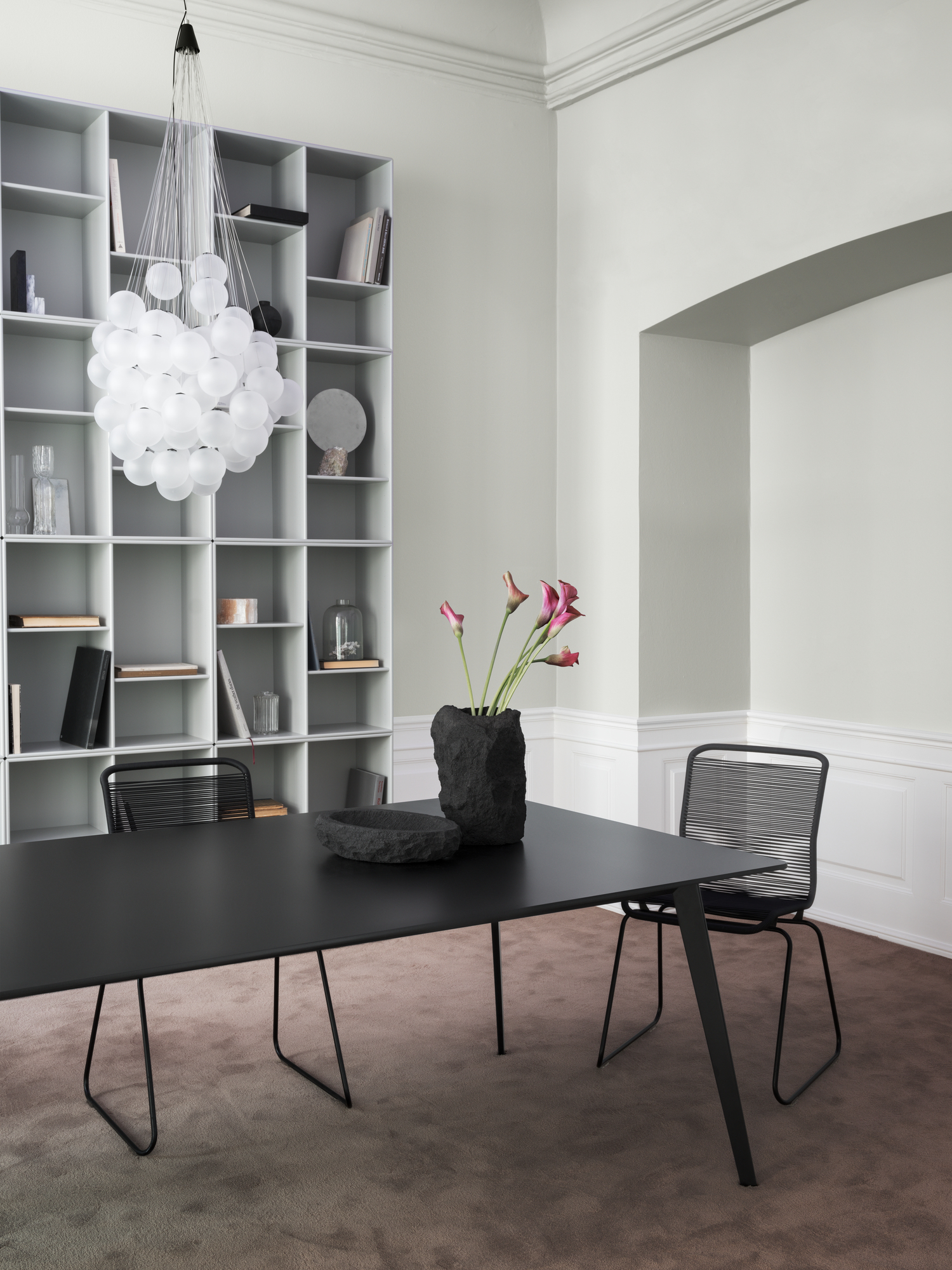 Schwarzer Esstisch mit zwei Panton One Stühlen und Dekoration in einem modernen Esszimmer.