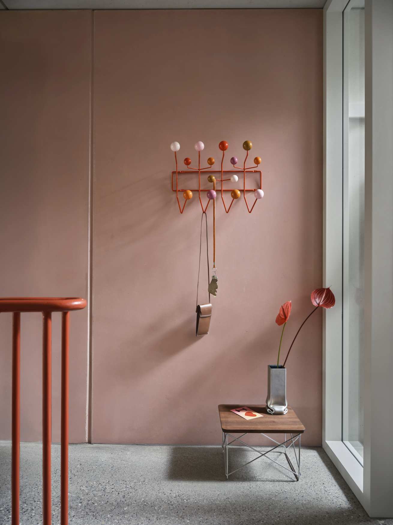 Eames Hang it all Garderobe Warm von Vitra an rosa Wand mit Accessoires.
