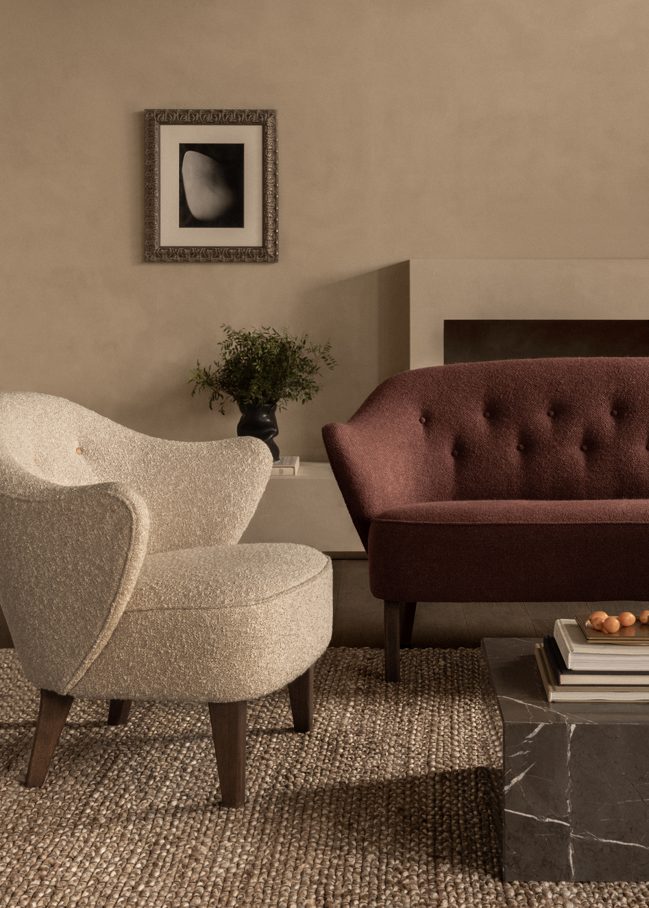 Beiger Ingeborg Sessel von Audo und rotes Sofa in stilvollem Wohnzimmer mit Teppich.