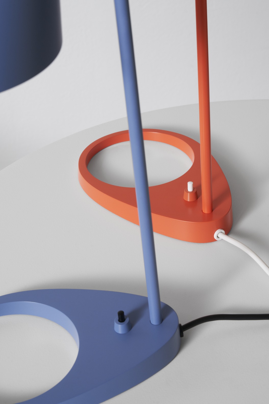 Detailaufnahme: Blaue und orangefarbene AJ Tischleuchte von Louis Poulsen, modernes Design, Schalter sichtbar.
