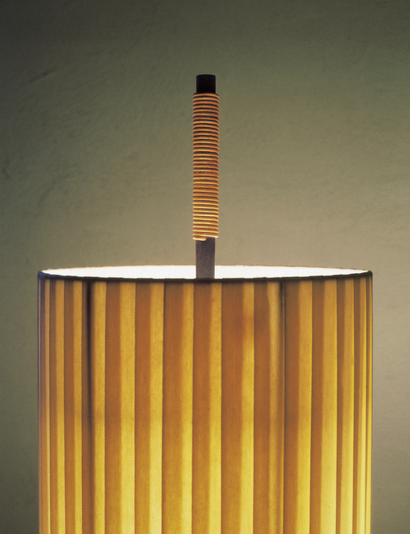 Nahaufnahme der Stehlampe mit gelbem Lampenschirm und geriffeltem Lampenfuß für stimmungsvolle Beleuchtung.