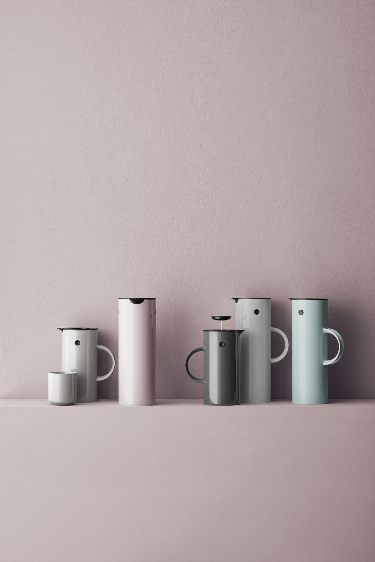 Produktfoto: Verschiedenfarbige Stelton Isolierkannen und French Press Kaffeebereiter auf rosa Hintergrund. Hochwertige Thermoskannen für Kaffee und Tee.