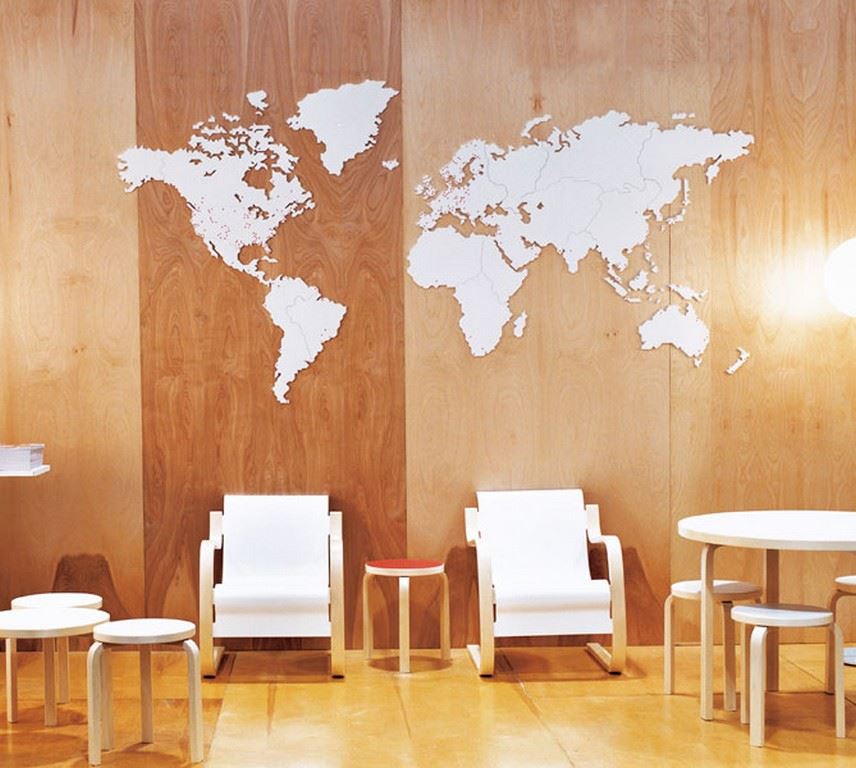 Helle Artek 42 Sessel aus Holz vor einer Wand mit Weltkarte, skandinavisches Design für Wohnzimmer.