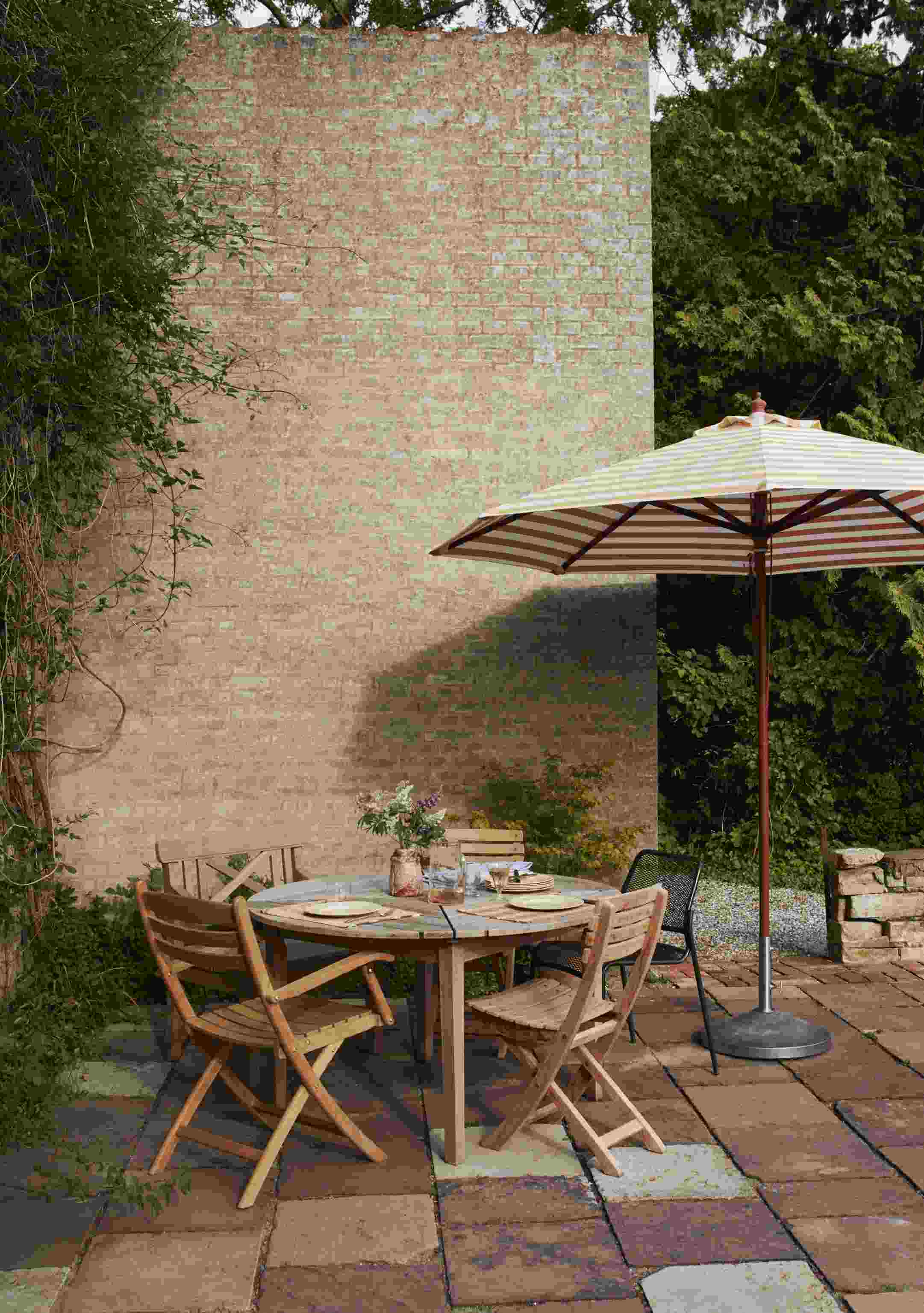 Drachmann Tisch von Skagerak by Fritz Hansen, runder Gartentisch aus Holz mit Stühlen und Sonnenschirm.