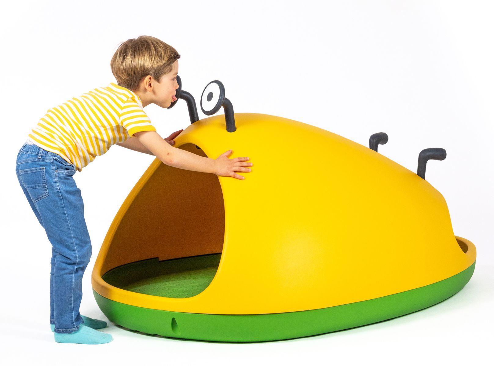 Junge betrachtet gelbe Nido Höhle von Magis, ein modernes Spielhaus für Kinder.