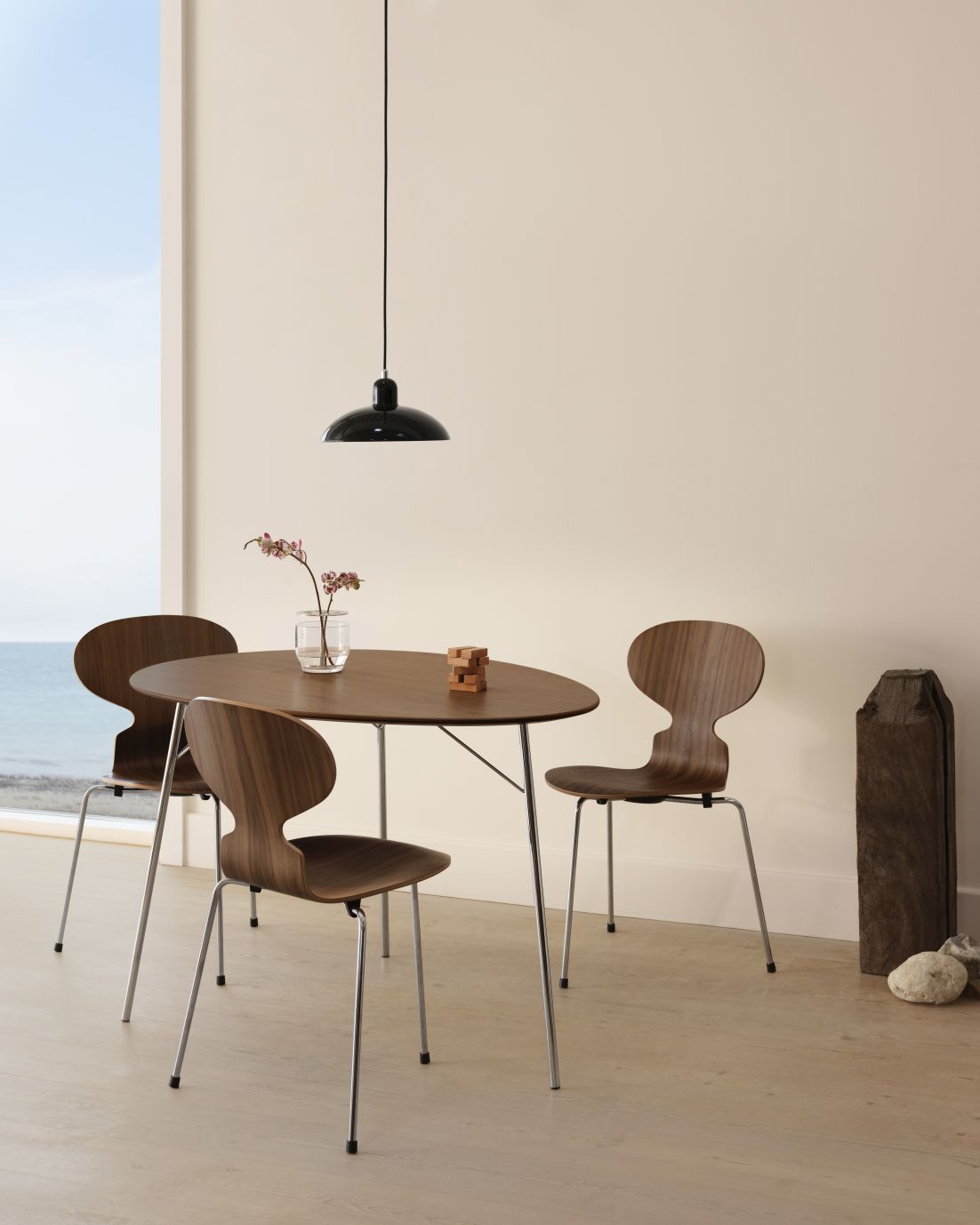 Fritz Hansen Egg Table Esstisch mit drei Holzstühlen und schwarzer Pendelleuchte in modernem Interieur.