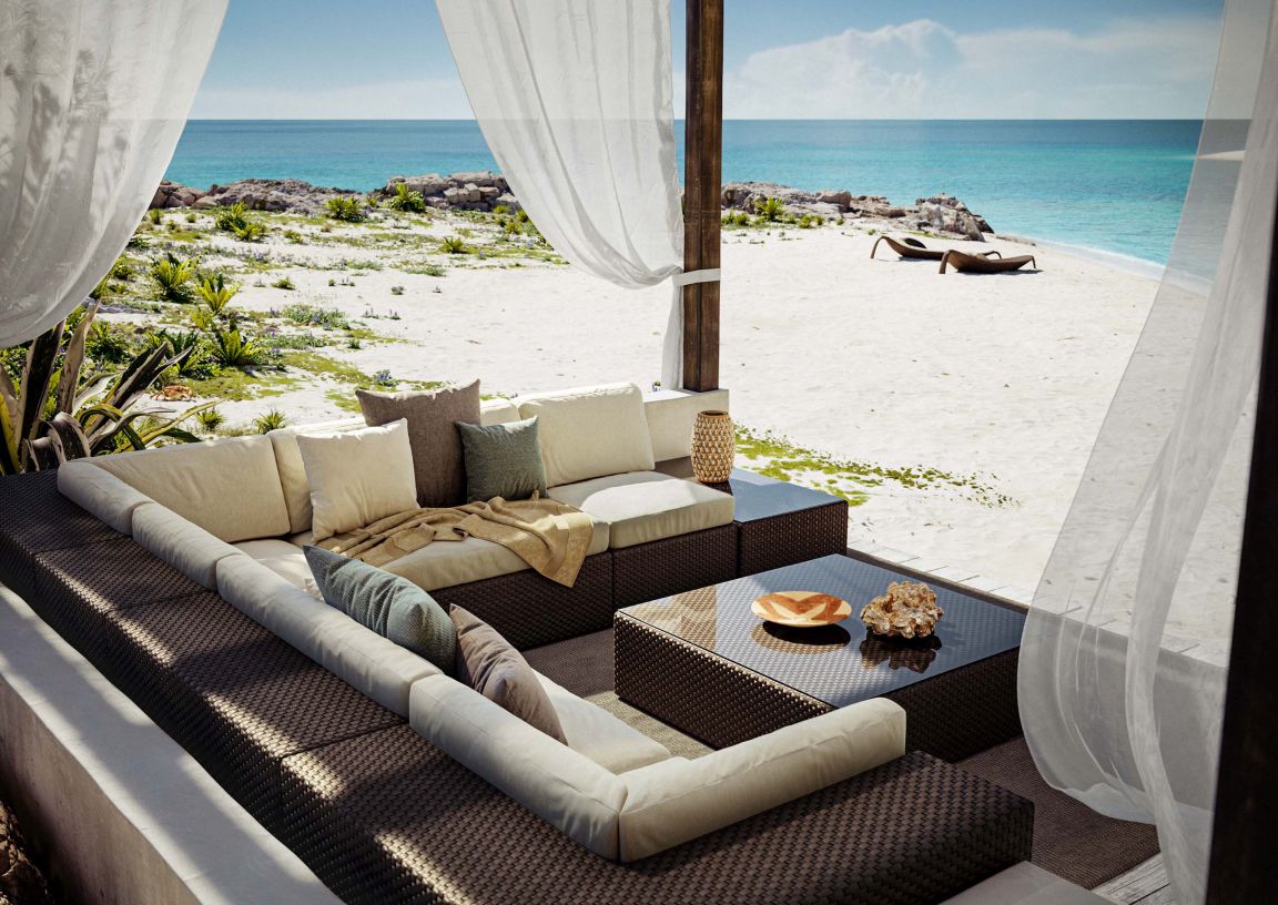 Braunes Rattan Lounge Set mit Kissen und Beistelltisch auf einer Terrasse mit Meerblick.