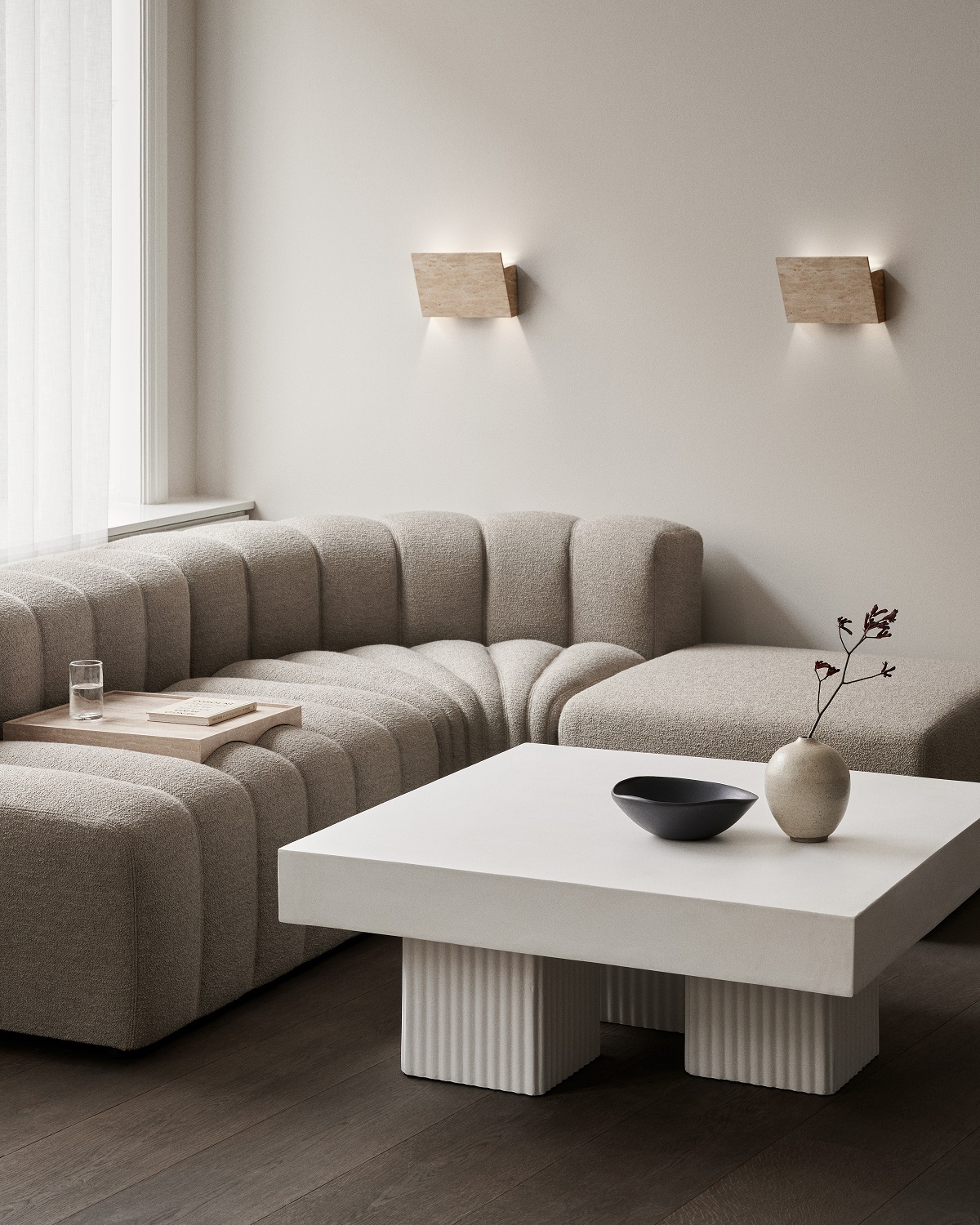 Heller Wohnraum mit Gear Square Couchtisch von Norr11, stilvollem Sofa und Wandleuchten.