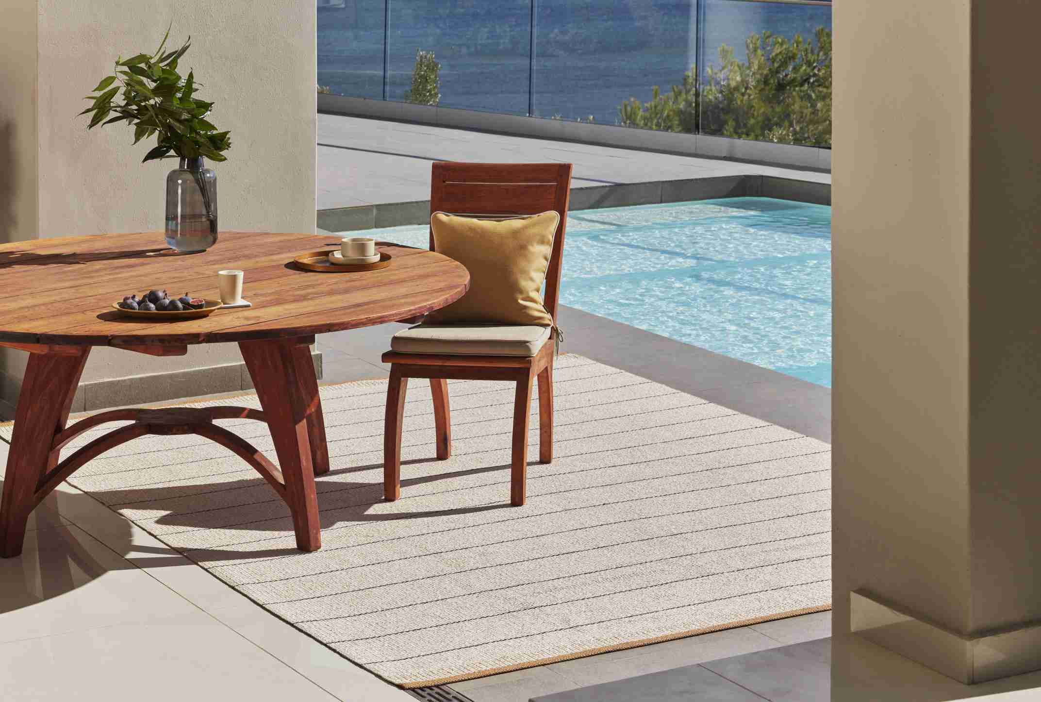 Belle Kunststoffteppich in Ocker (230x320 cm) auf Terrasse mit Tisch und Stuhl. Outdoor Teppich.