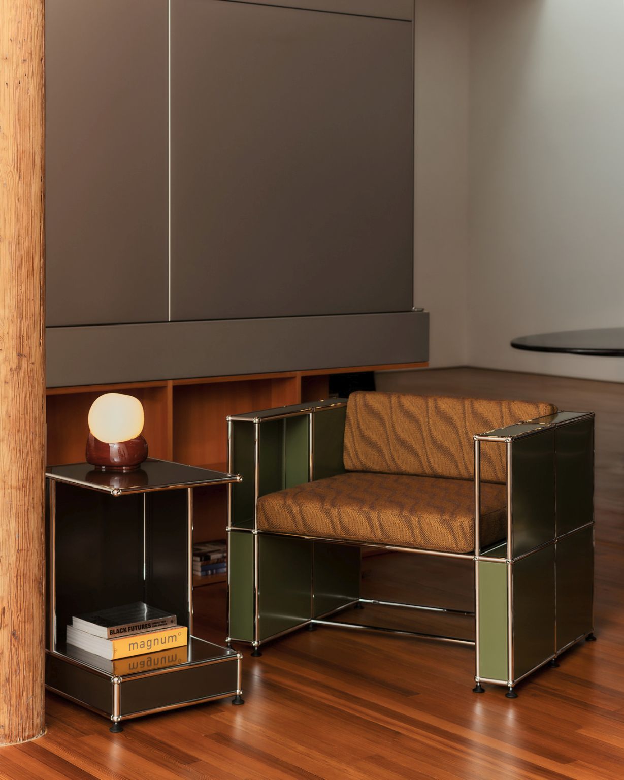 USM Haller Beistelltisch Arkad von Armando Cabral in Grün mit Lampe und Sessel im Wohnzimmer.