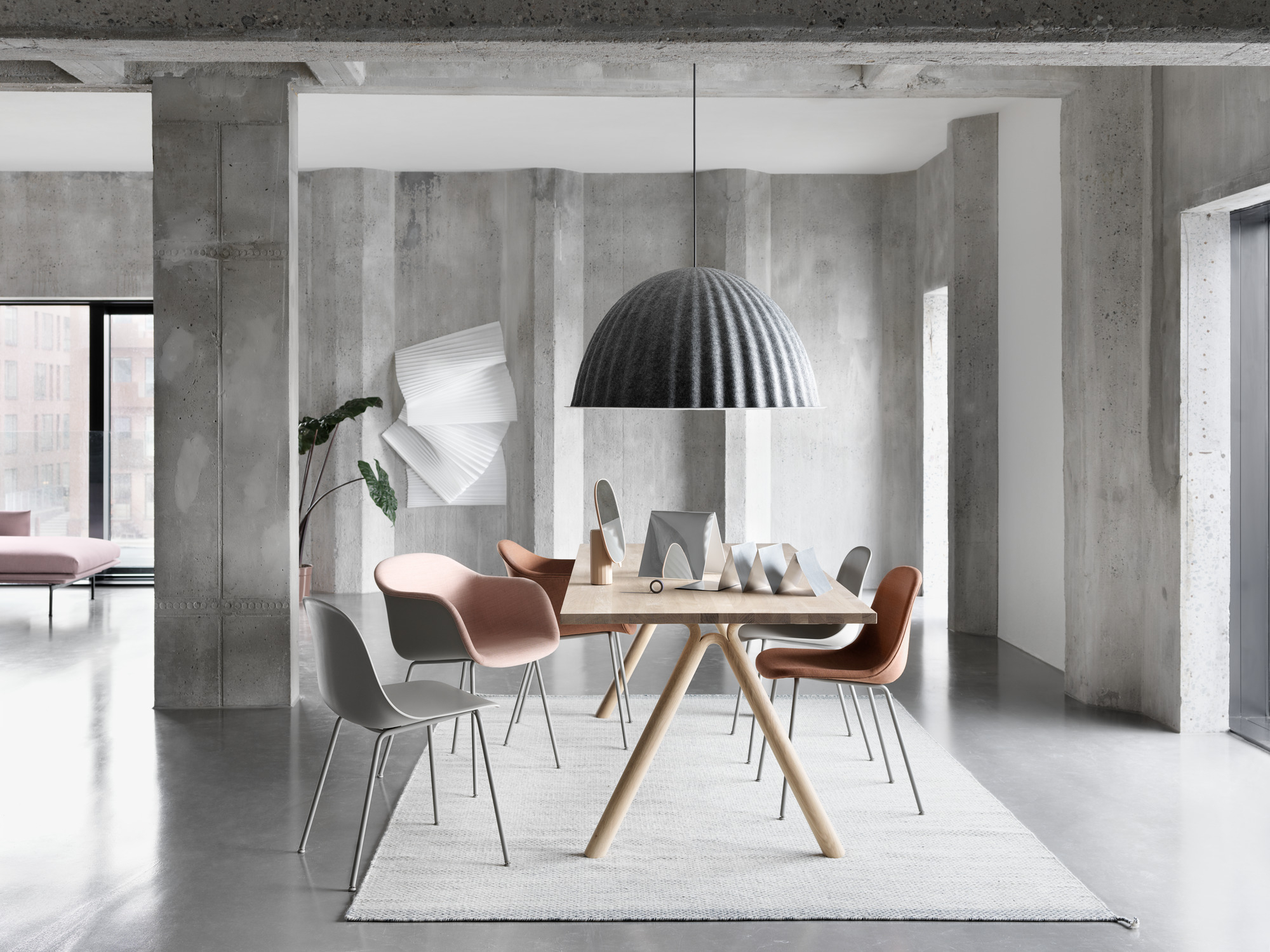 Esszimmer mit Holztisch, Teppich und Muuto Fiber Side Chairs mit Tube Base in verschiedenen Farben.