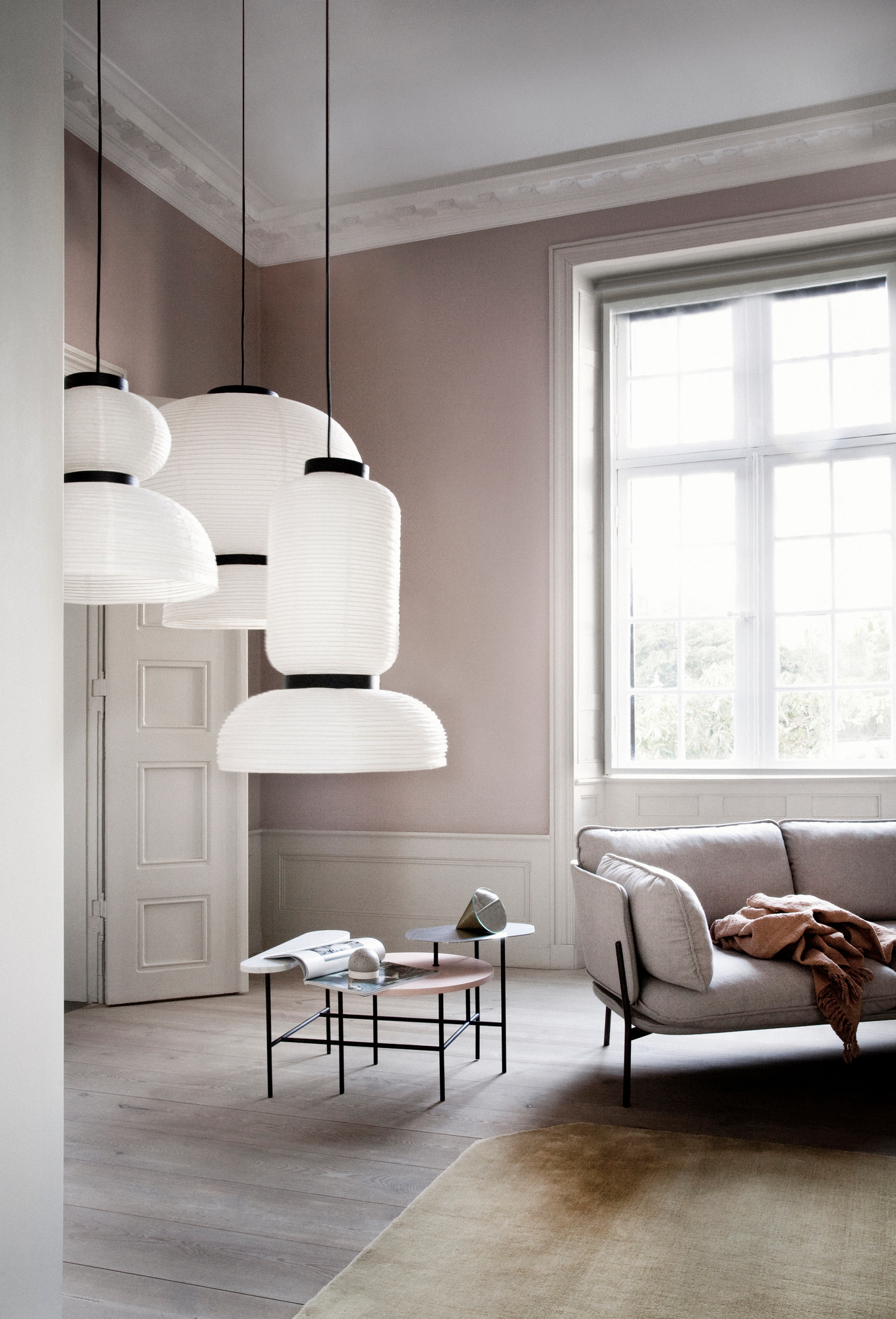 Wohnzimmer mit grauem Cloud Sofa von AndTradition, Beistelltischen und dekorativen Pendelleuchten.