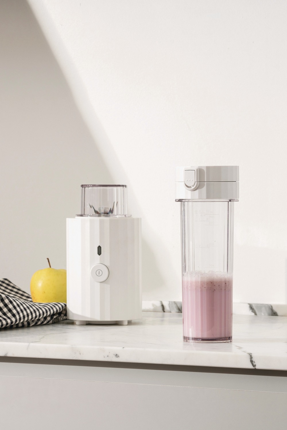 MDL17 Plissé Smoothie Maker: Weißer Mini-Mixer mit rosa Smoothie und gelbem Apfel.