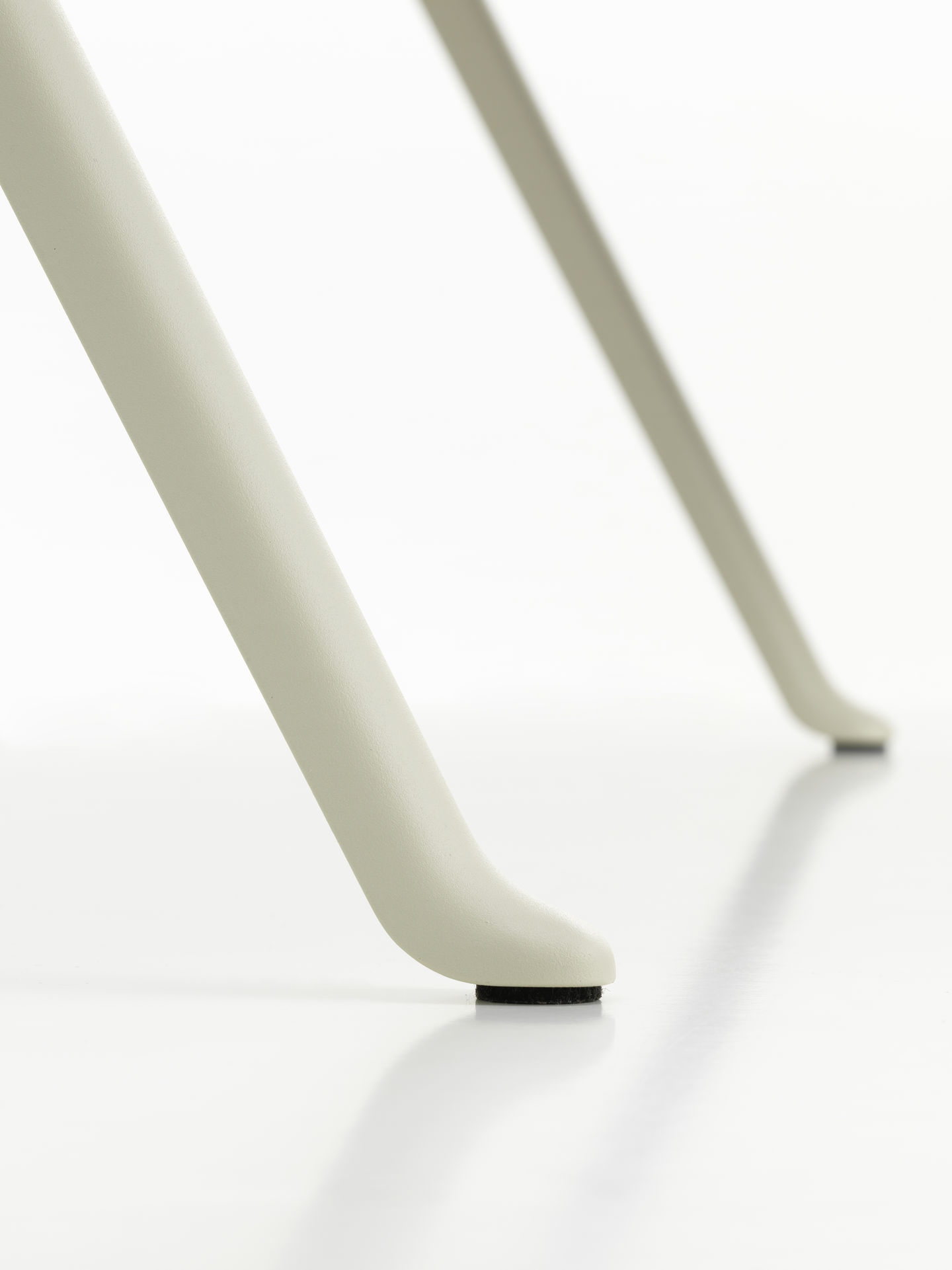 Detailaufnahme der hellgrauen Beine des Vitra Courier Schreibtischs mit schwarzen Filzgleitern auf einem weißen Hintergrund.