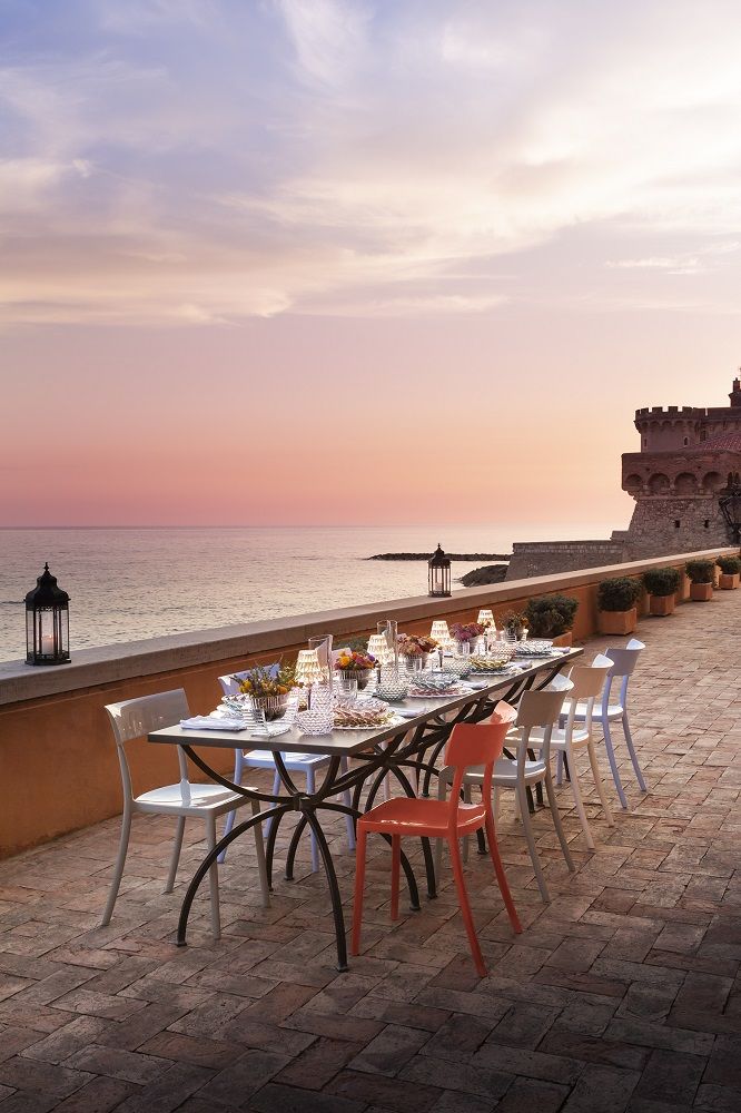 Esstisch am Meer mit Catwalk Stühlen von Kartell in Weiß und Orange, modernes Outdoor-Mobiliar.