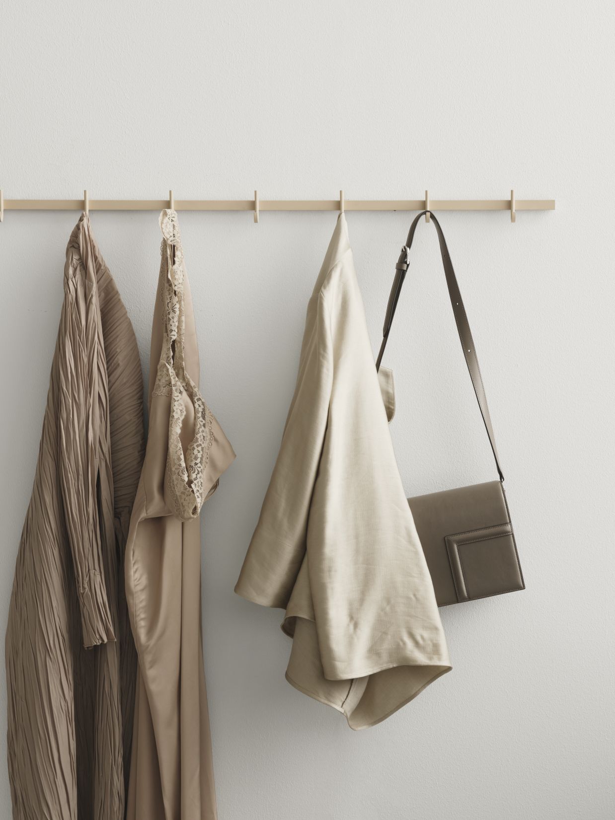 Weiße Relief Hakenleiste von String Furniture mit Kleidung und Tasche an der Wand.