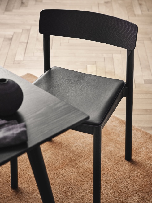Detailaufnahme eines schwarzen AndTradition In Between Tisches mit passendem Stuhl auf einem Teppich.