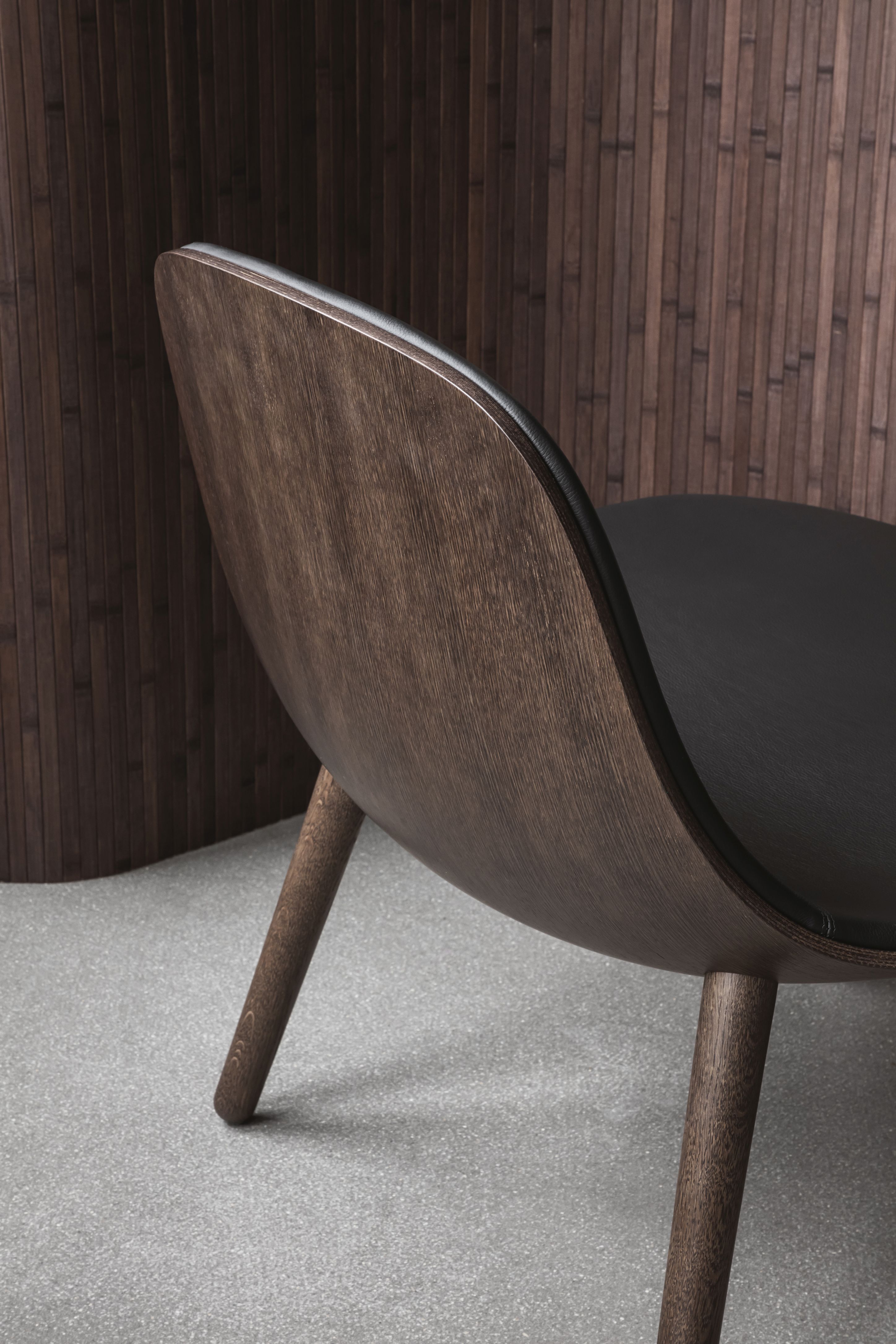 EVA SOLO Abalone Lounge Stuhl aus geräucherter Eiche, Detailansicht von hinten mit schwarzer Sitzfläche.