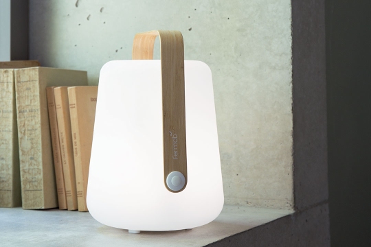 Nahaufnahme der leuchtenden Fermob Balad Akku-Tischleuchte mit Bambusgriff, ideal als mobile Lampe.