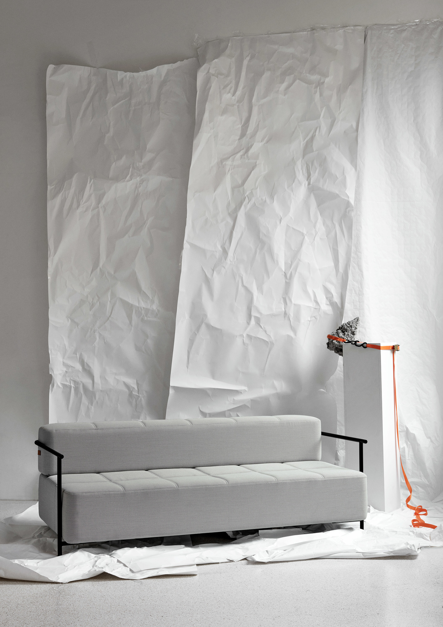 Graues Daybe Schlafsofa mit Armlehnen und schwarzem Gestell vor weißem Hintergrund. Moderne Schlafcouch für Wohnzimmer.