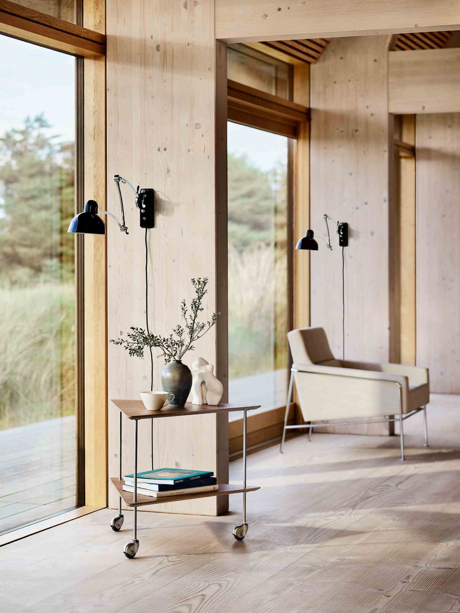 Schwarze Kaiser idell Wandleuchte von Fritz Hansen mit Messingdetails in modernem Wohnraum. Design Lampe.