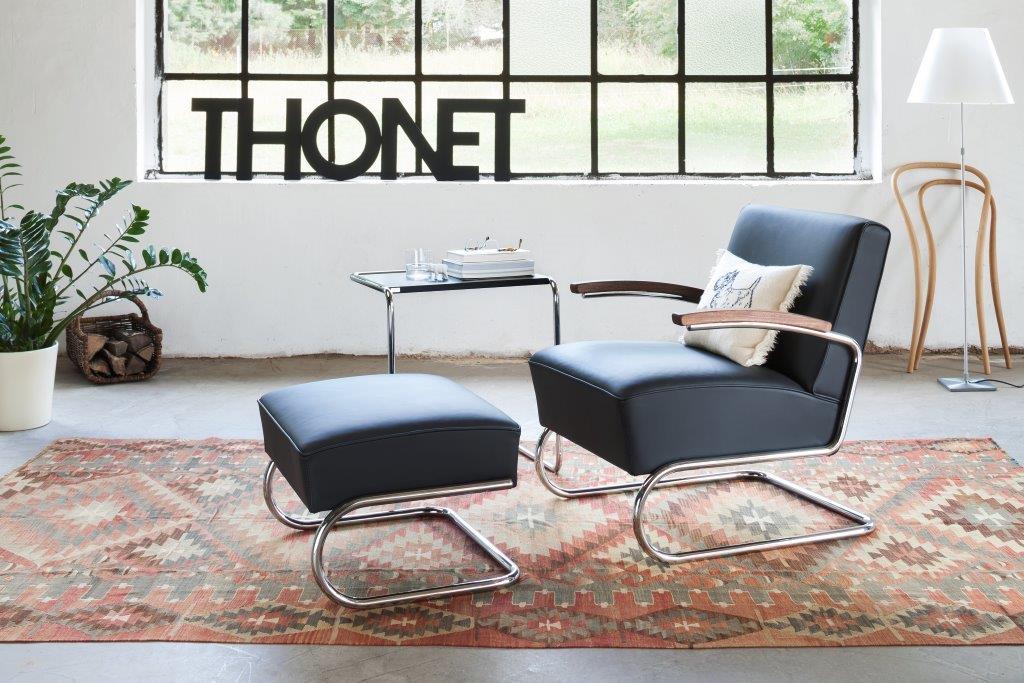 S 411 H Hocker Leder Thonet: Schwarzer Lederhocker mit verchromtem Stahlrohrgestell vor hellem Hintergrund.