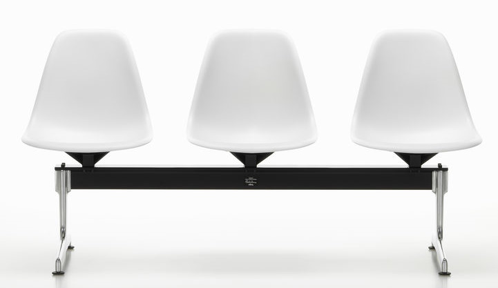 Eames Side Chair auf Traverse von Vitra, drei weiße Kunststoffschalen auf schwarzem Gestell.