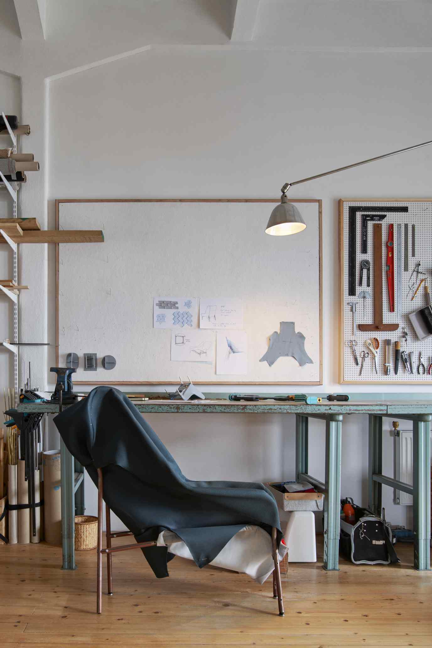 Werkstatt-Szene mit Hay 02 Lounge Chair Sessel, teilweise mit Stoff bedeckt, umgeben von Werkzeugen und Designskizzen.
