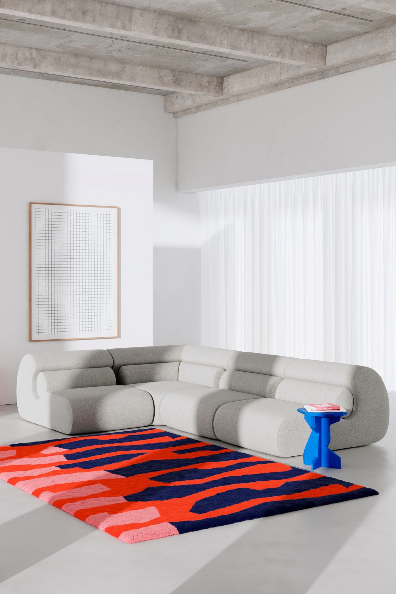 Helles Wohnzimmer mit grauem Modulsofa, blauem Beistelltisch und modernem Teppich in Rot und Blau.