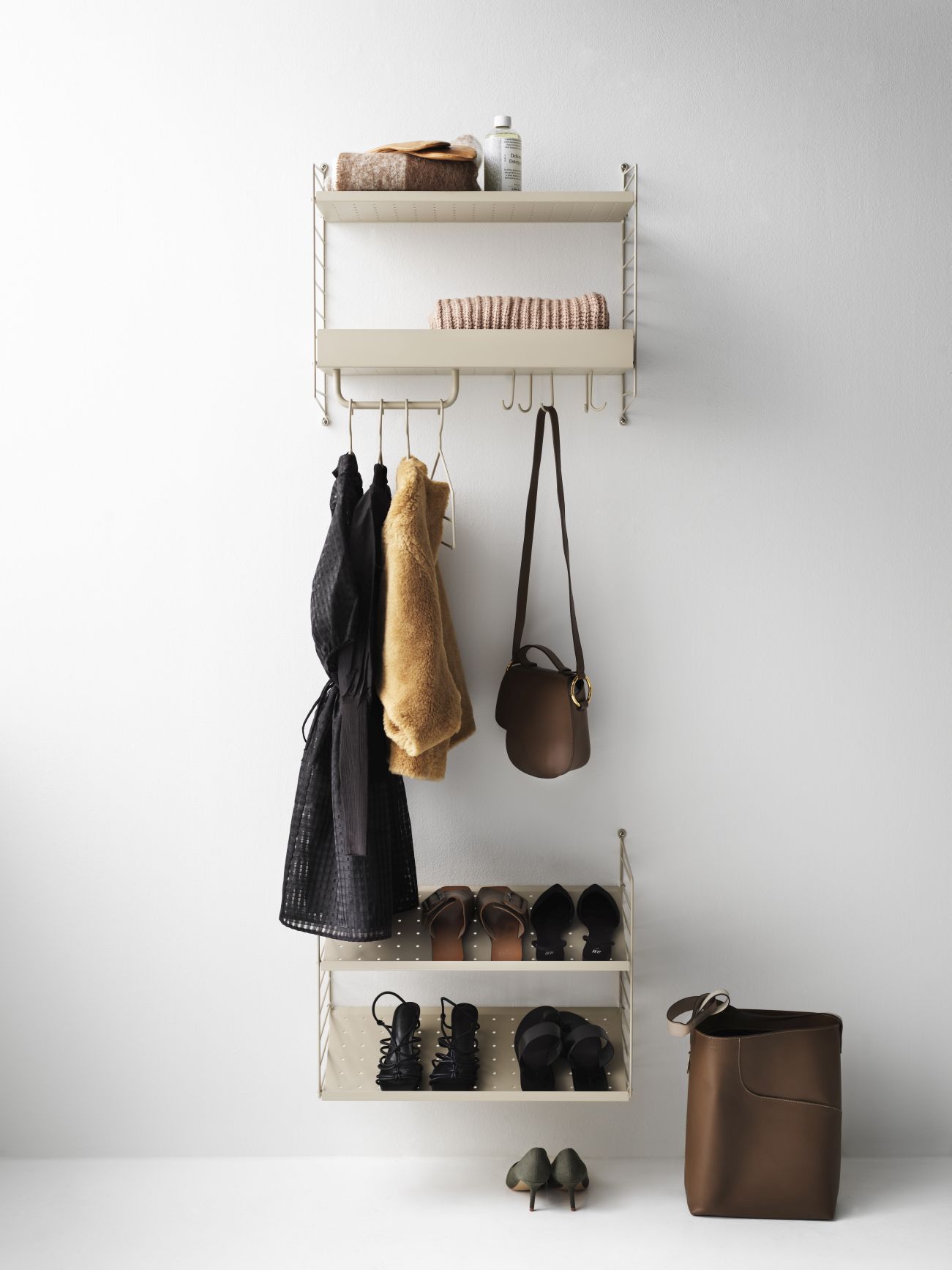 Detailaufnahme eines String Regals mit Hakenleiste und Kleidung, Schuhen und Accessoires.
