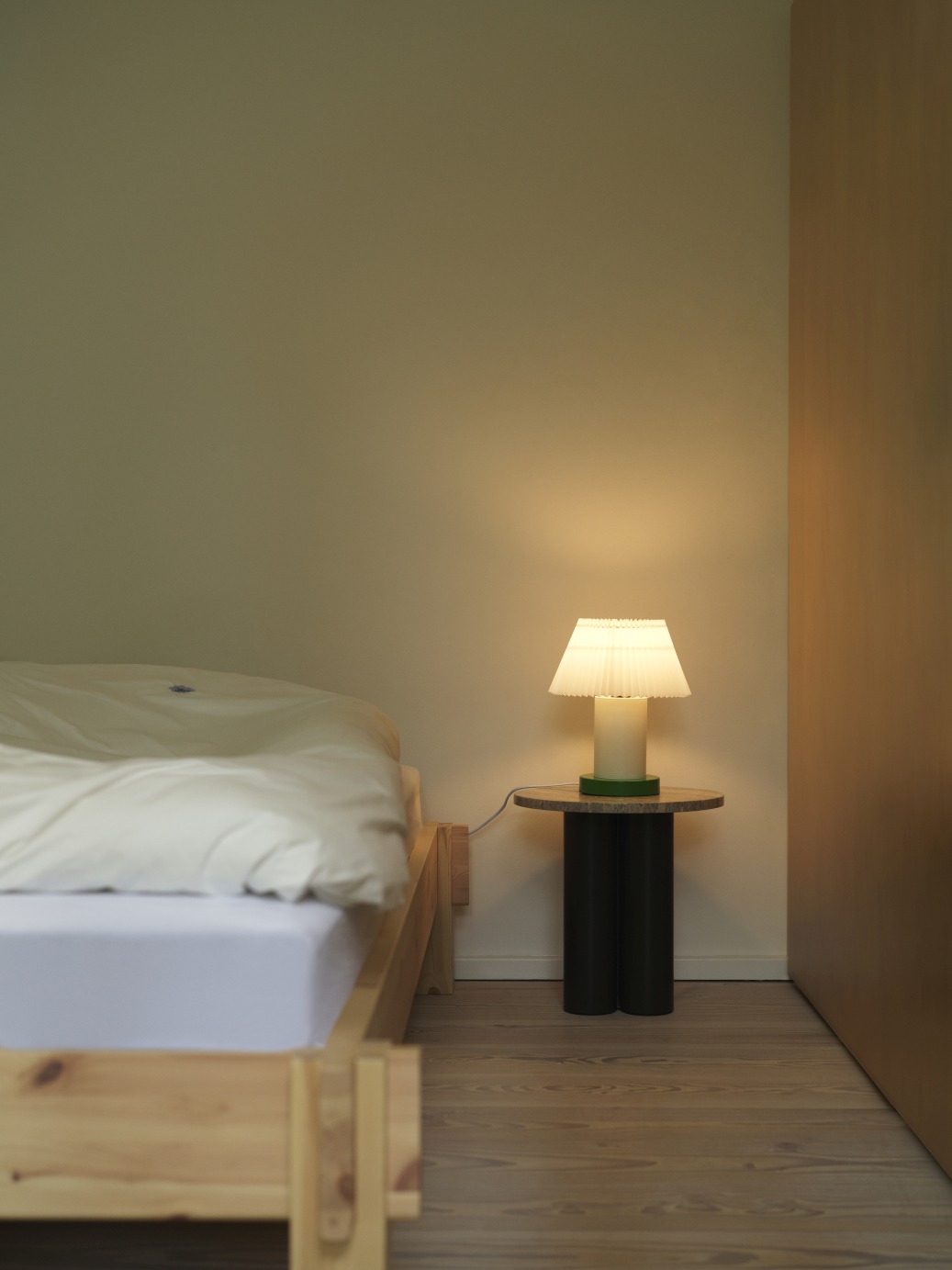 Normann Copenhagen Dit Coffee Table Beistelltisch im Schlafzimmer neben einem Bett mit Lampe.