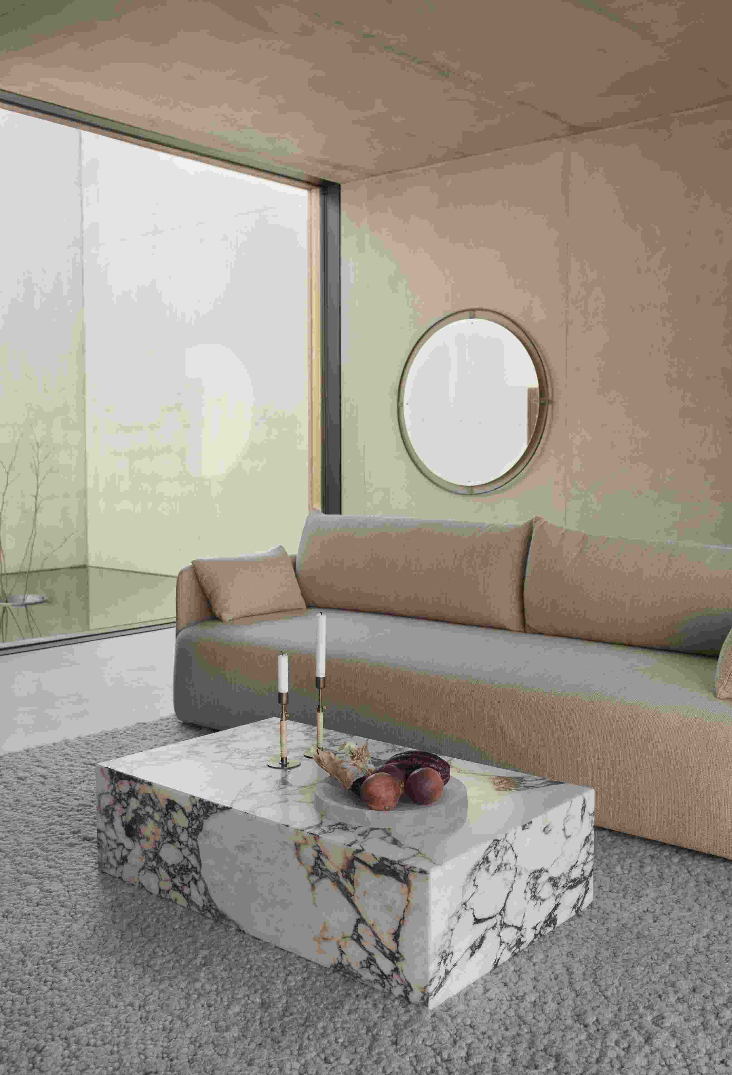 Audo Copenhagen Plinth Tisch aus Marmor im Wohnzimmer mit Sofa und Dekoration.
