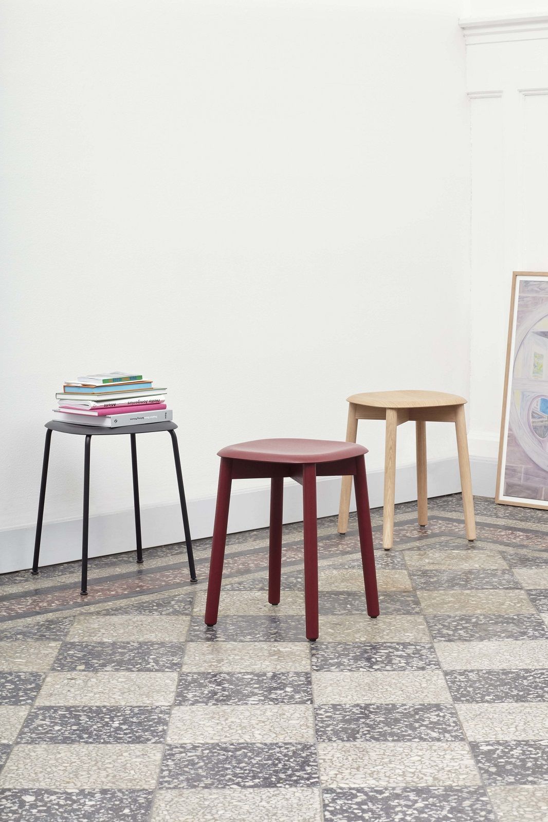 Drei Hay Soft Edge Hocker in Schwarz, Rot und Holz auf gemustertem Boden.