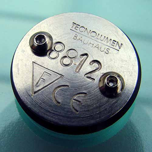 Detailaufnahme der Tecnolumen WG24 Wagenfeld Tischleuchte: Bodenplatte mit Herstellerlogo, Seriennummer und Schrauben.
