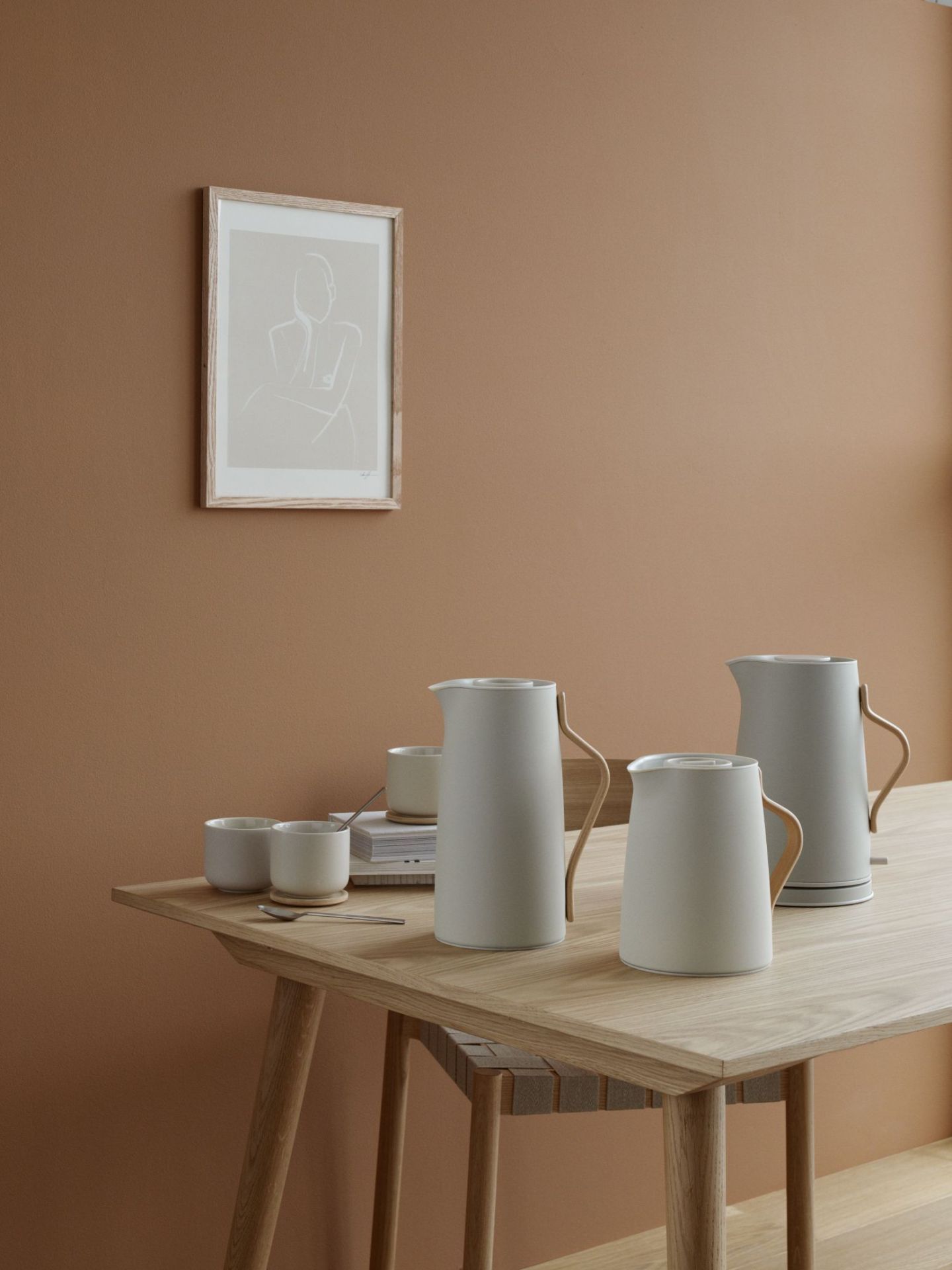 Helle Isolierkannen und Tassen auf Holztisch, skandinavisches Design für Tee, Kaffee und Heißgetränke.
