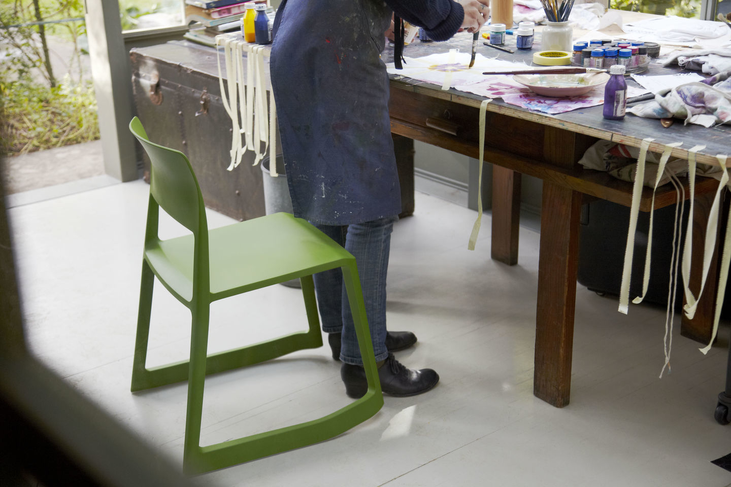 Grüner Tip Ton RE Stuhl von Vitra neben Person beim Malen an einem Tisch.