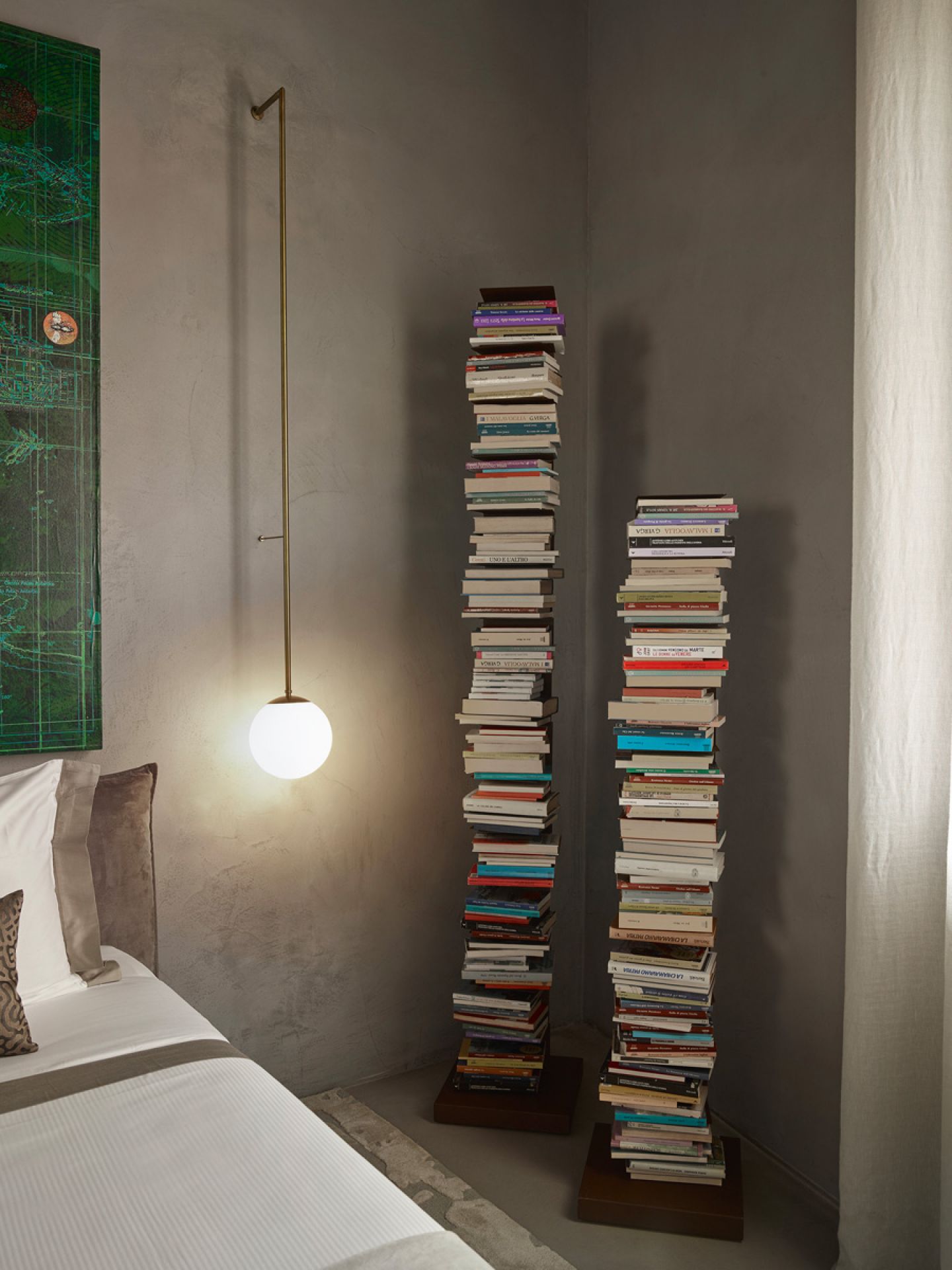Zwei Ptolomeo Bücherregale neben einem Bett, gestapelte Bücher als Designelement, moderne Einrichtung.