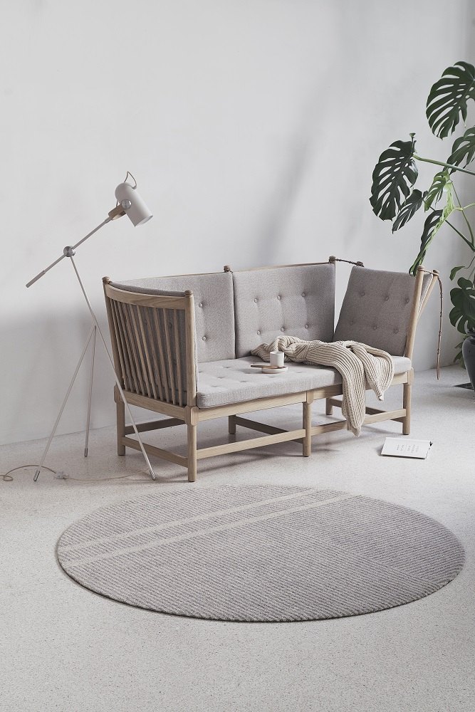 Løype Fußmatte in Breezy Beige vor hellem Sofa und Zimmerpflanze, stilvolle Indoor und Outdoor Fußmatte.