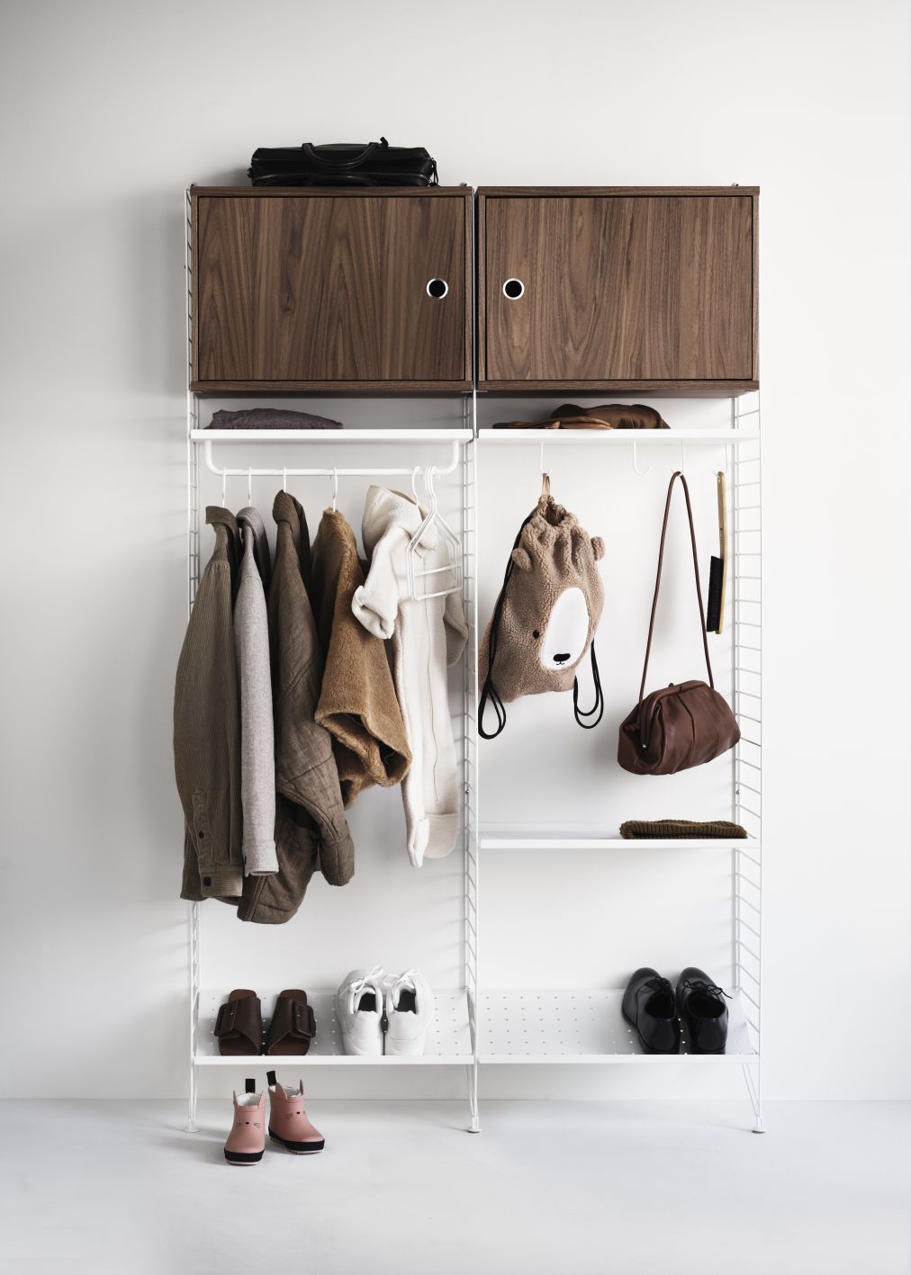 Weißes Regalsystem mit Kleidung, Schuhen und Accessoires, ergänzt durch zwei Holzschränke zur Aufbewahrung.