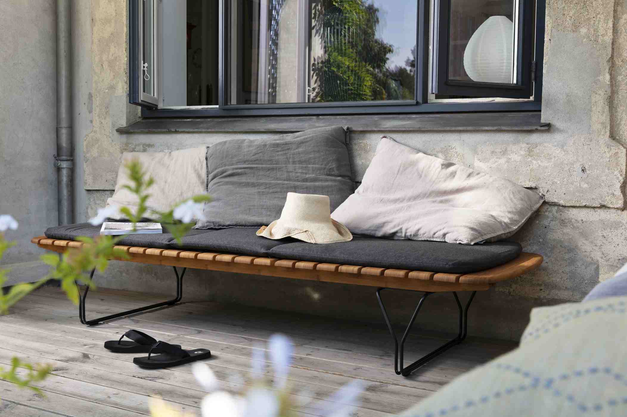 Molo Outdoor Cushion Kissen für Houe Sonnenliege, graue Sitzauflage und Dekokissen auf Holzbank.