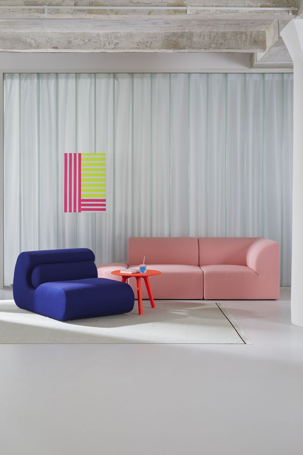 OLA Sofa und Pouf in Blau und Rosa mit rotem Tisch in modernem Wohnzimmer.