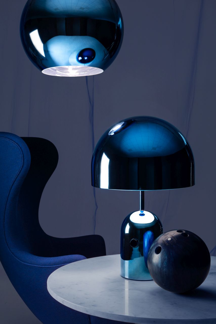 Blaue Bell Tischleuchte LED von Tom Dixon auf Marmortisch, daneben ein Bowlingball und ein Sessel.
