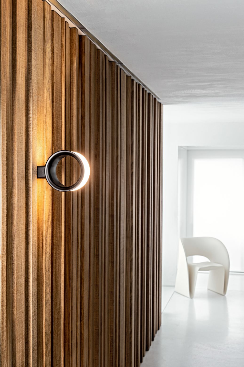Lost Wandleuchte von Magis: Runde Designleuchte an einer Holzwand, modernes Lichtobjekt.