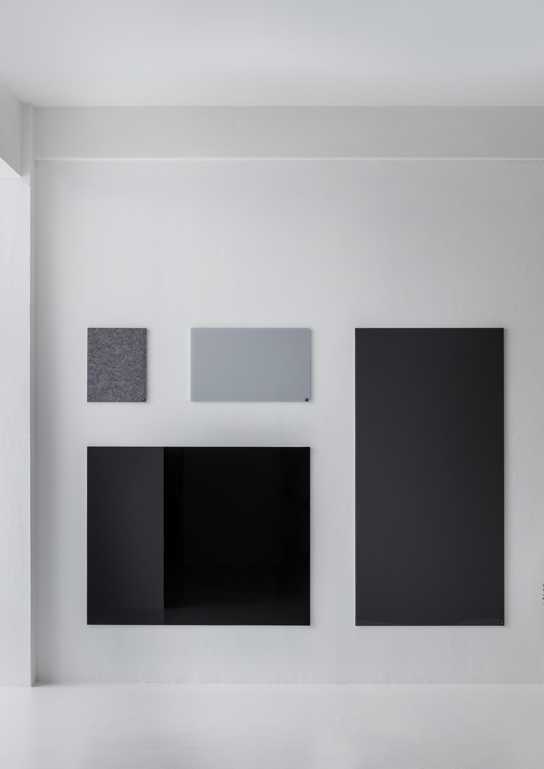 Wand mit verschiedenen Chat Board Glastafeln in Schwarz und Grau, inklusive Filz-Pinnwand, für Büro und Zuhause.