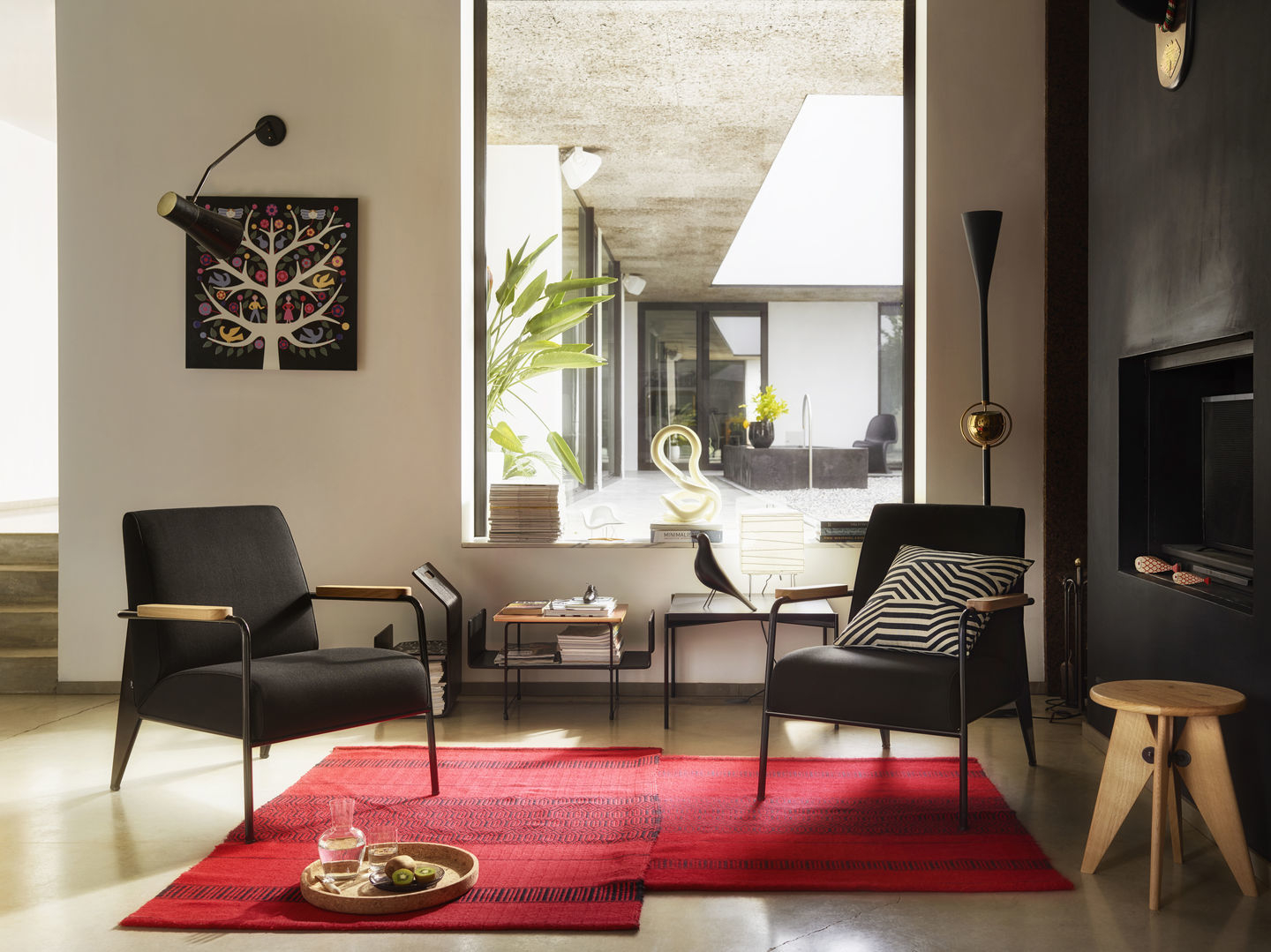 Schwarzer Fauteuil De Salon Sessel von Vitra im modernen Wohnzimmer mit rotem Teppich und Designelementen.