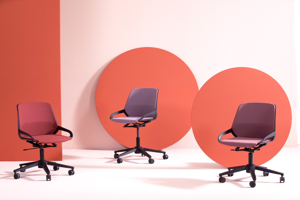 Numo Task Bürodrehstühle von Aeris in Rot und Lila mit Säule und Rollen vor farbigen Kreisen.