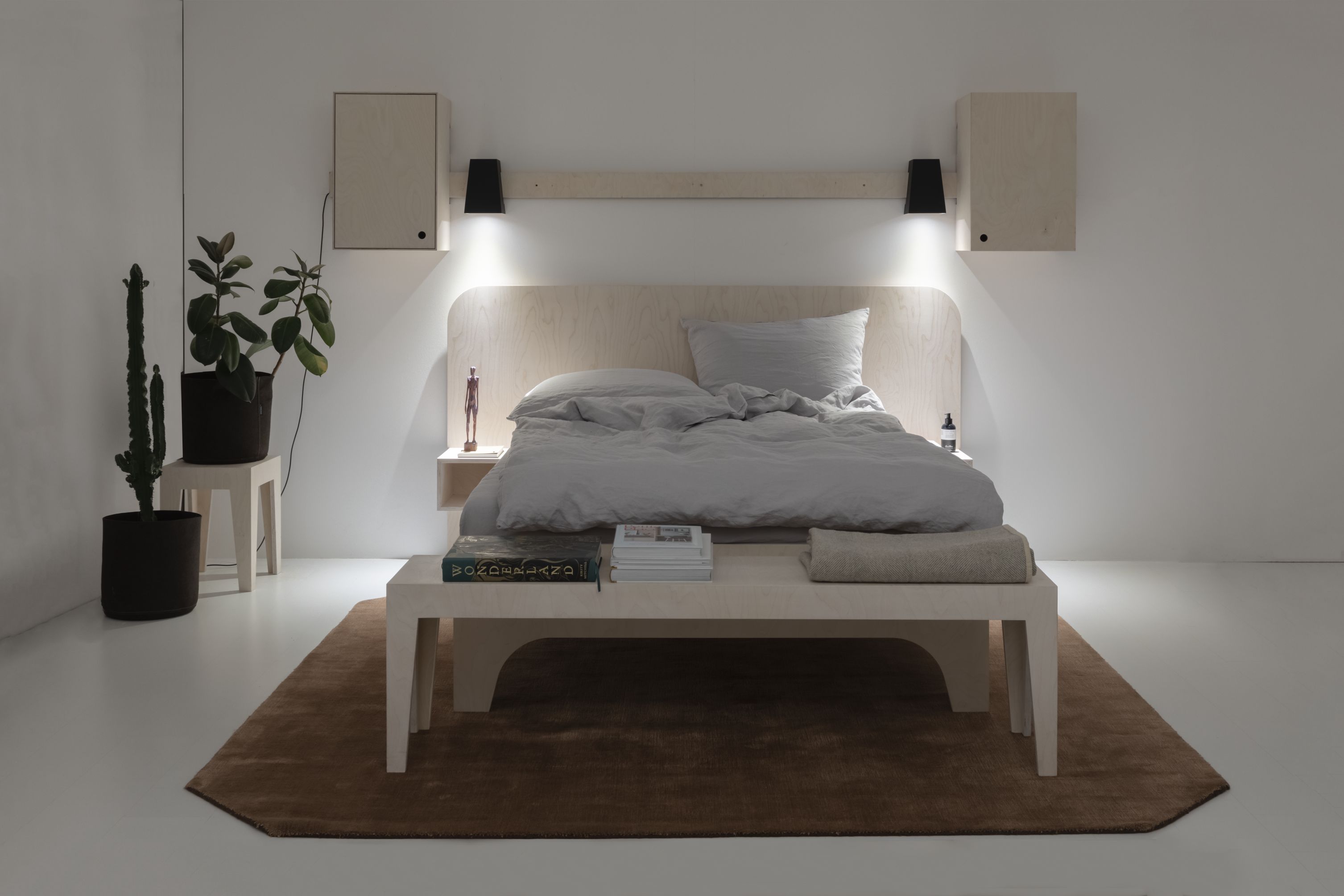 VALENTINA Bett aus hellem Holz mit grauer Bettwäsche, Nachttisch, Lampen und Dekoration für ein modernes Schlafzimmer.