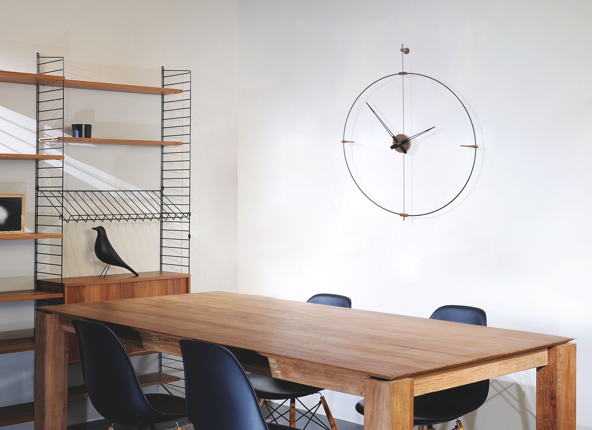 Esszimmer mit Holztisch, Stühlen und einer runden Mini Bilbao Wanduhr von Nomon an der Wand.